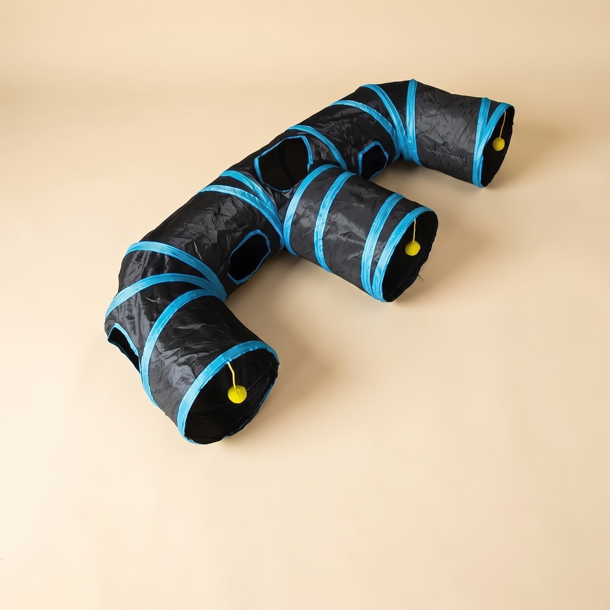 Black 3 way cat tunnel with blue trim and peep holes on a plain cream background