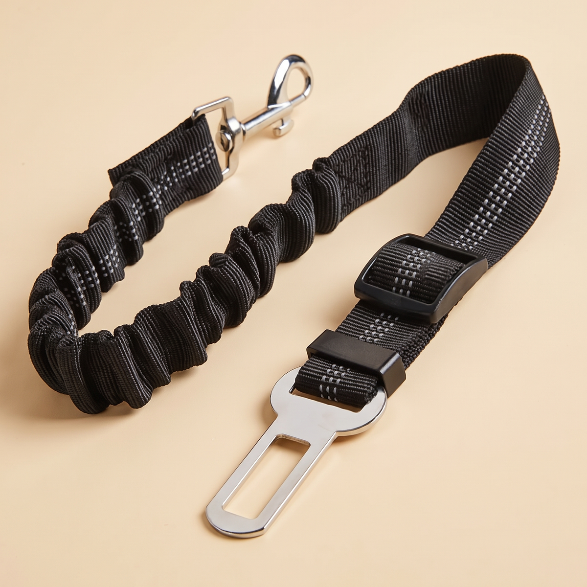 Black bungee dog car seat belt with swivel clip on a cream background