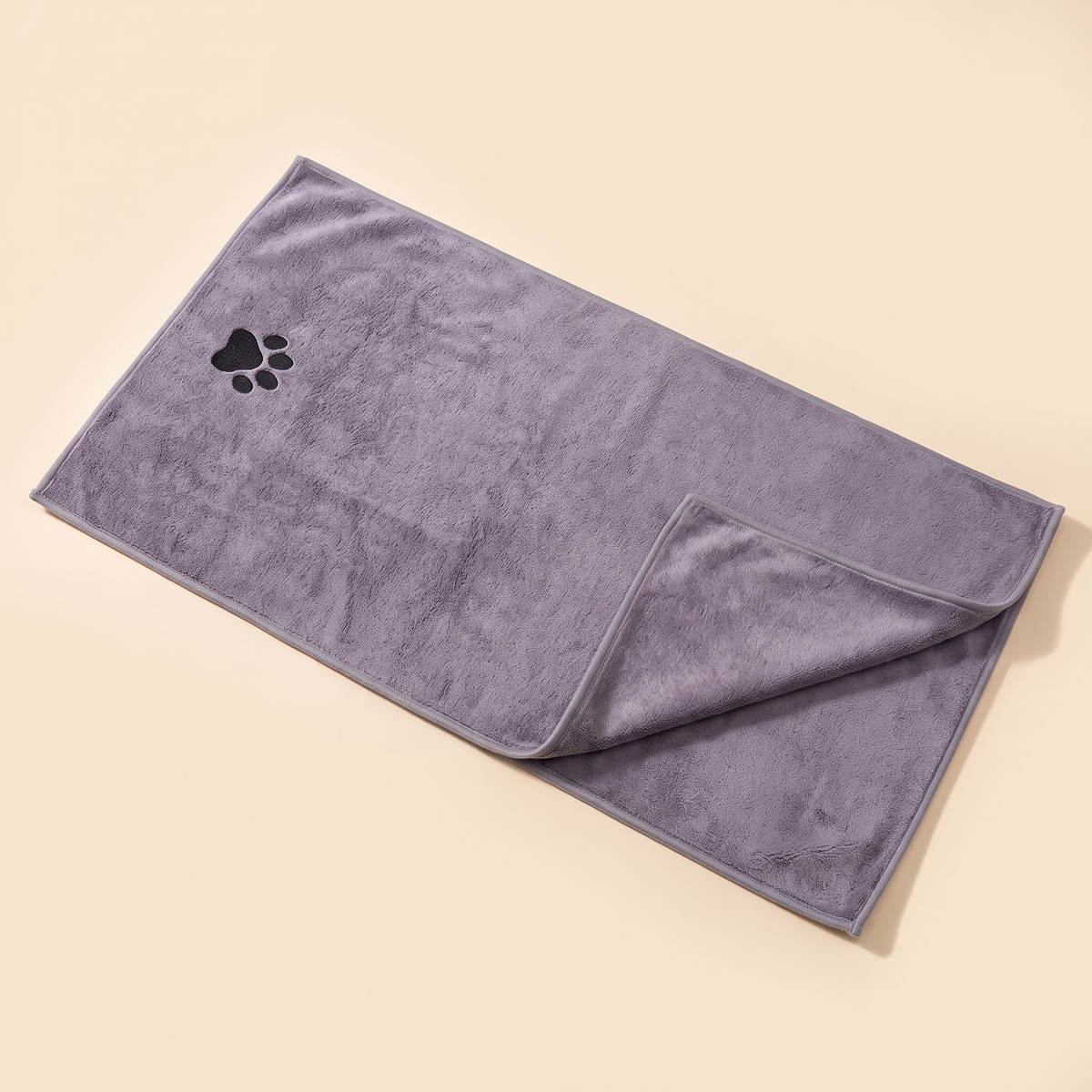 Grey microfibre dog drying towel with paw motif laid flat on a cream background