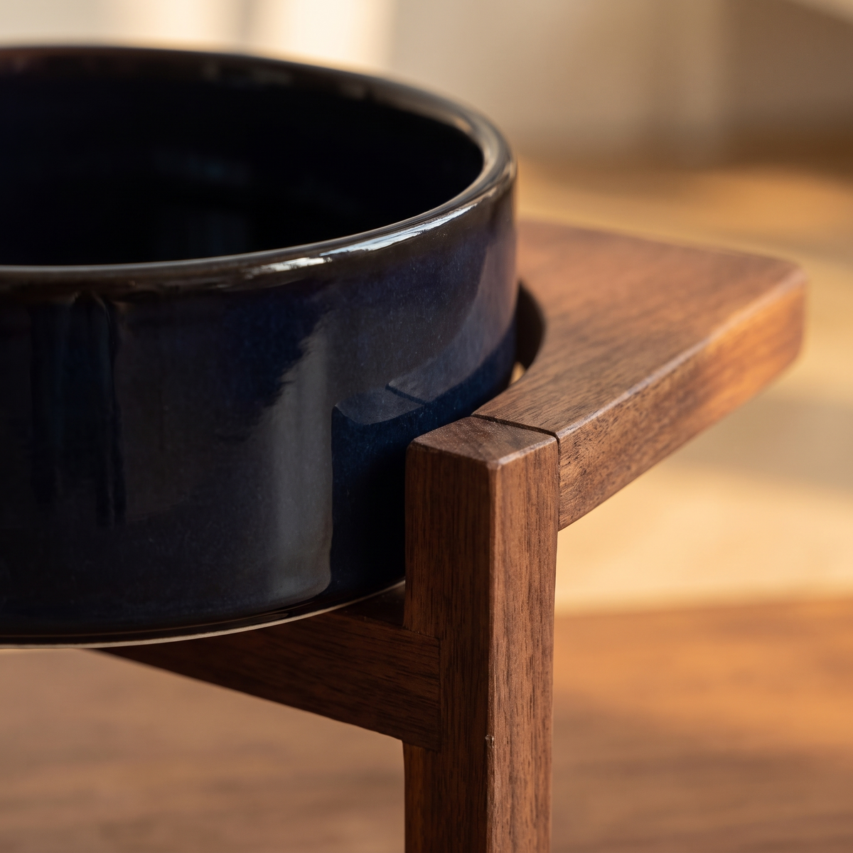 Close-up of the navy glazed ceramic bowl rim resting in the solid walnut frame