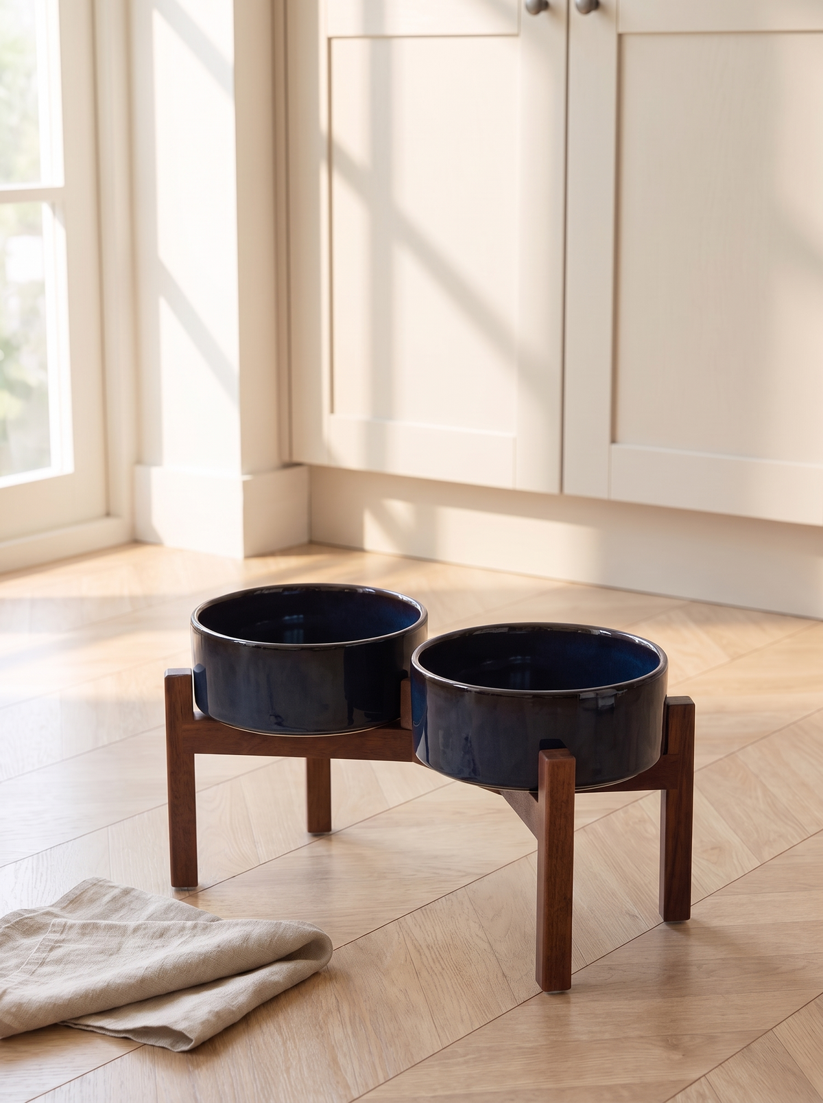 K06B Elevated navy ceramic double dog bowl feeder on a warm oak kitchen floor