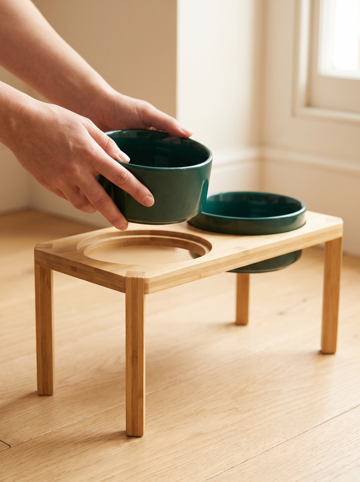 K02C Hands lifting one teal ceramic bowl out of the wooden feeding stand for washing