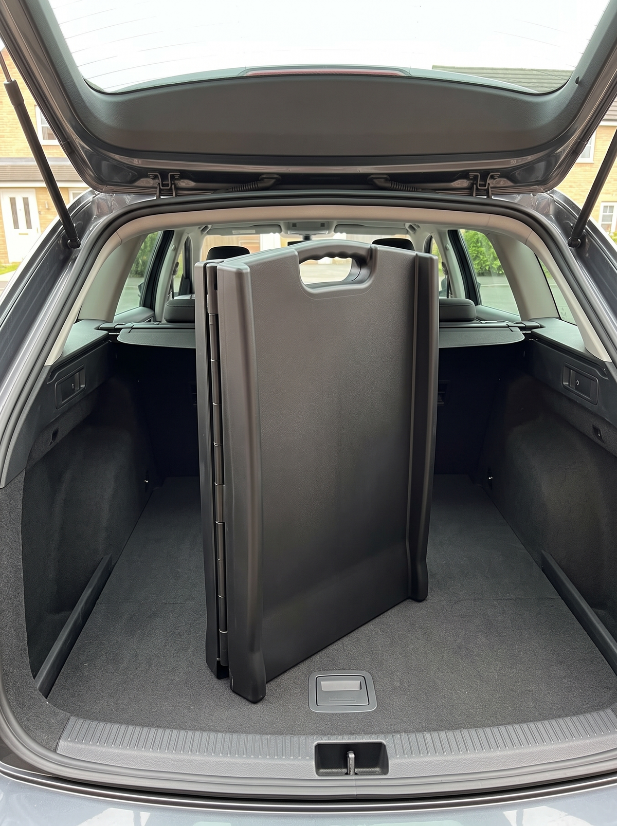 The dog car ramp folded in half and stowed upright in a car boot