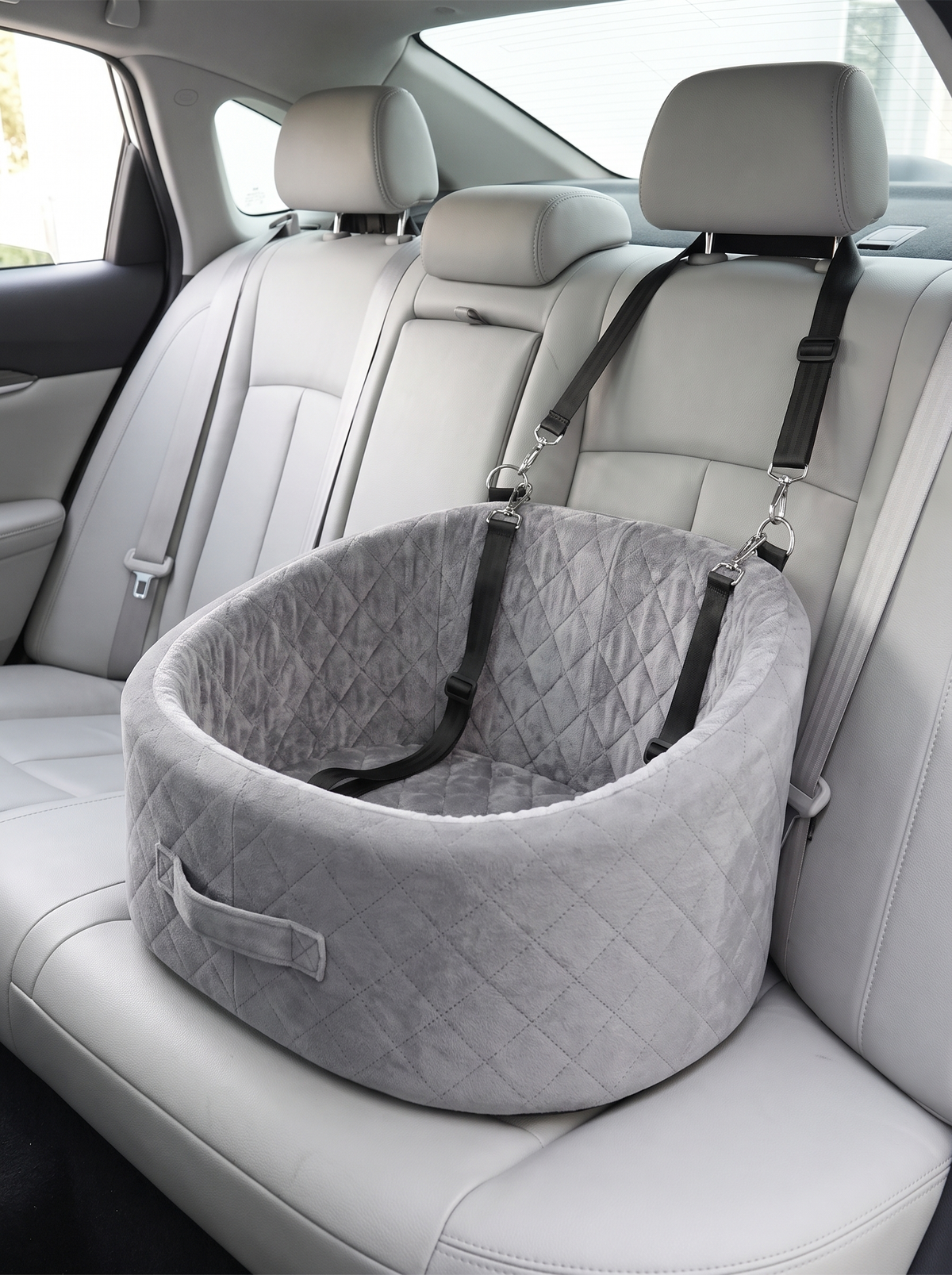 The grey quilted booster seat strapped to the rear headrests of a car