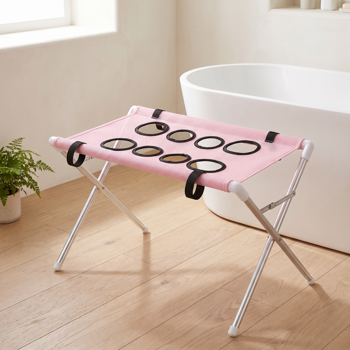 Pink mesh dog bath hammock stand on a silver folding frame beside a white bath