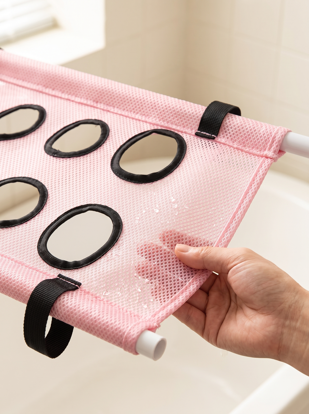 Hand pressing the soft pink mesh of the dog bath hammock stand, showing the black-edged leg openings