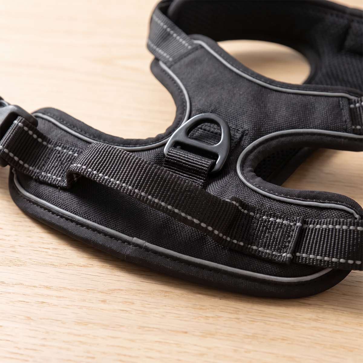 Close-up of the grab handle, metal ring and reflective stitching on the black dog harness