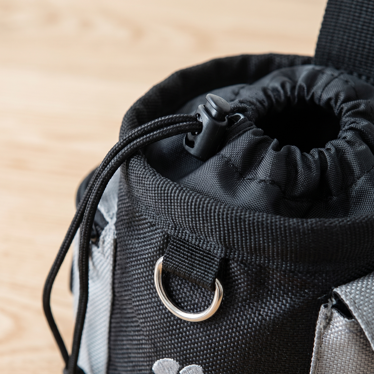 Close-up of the drawstring top, cord lock and metal D ring on the dog treat pouch
