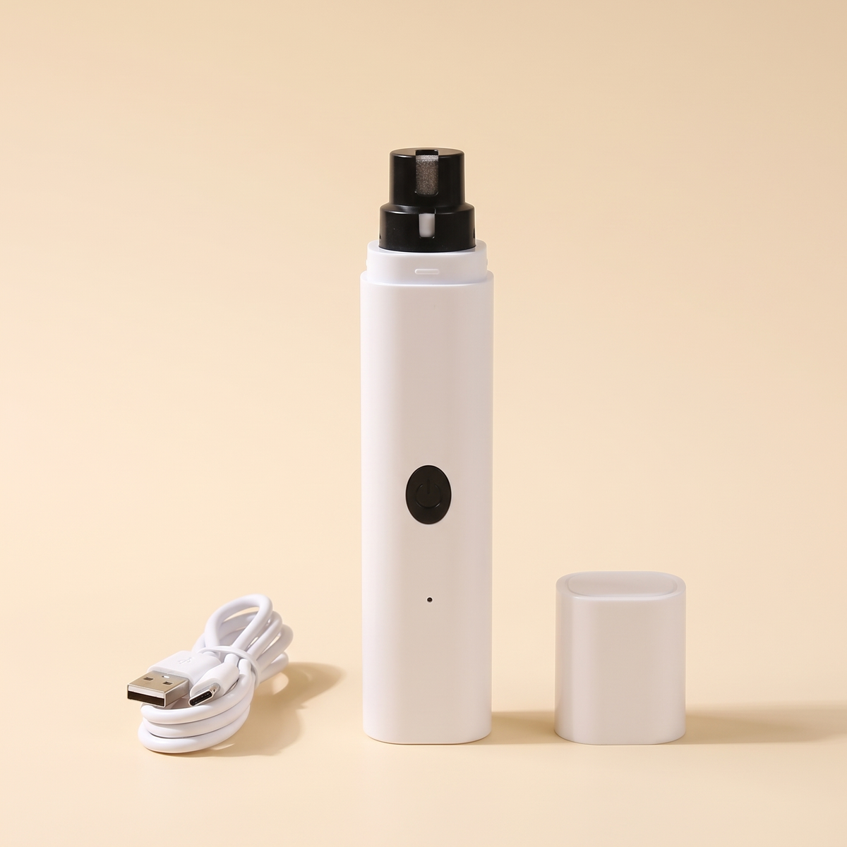 White dog nail grinder with protective cap and USB charging cable on a plain cream background