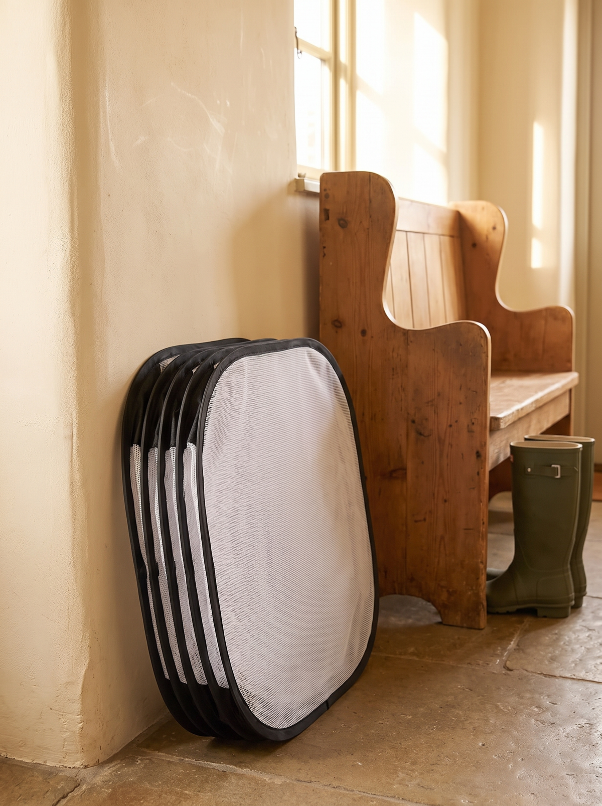 Pop up pet playpen folded flat and leaning against a hallway wall