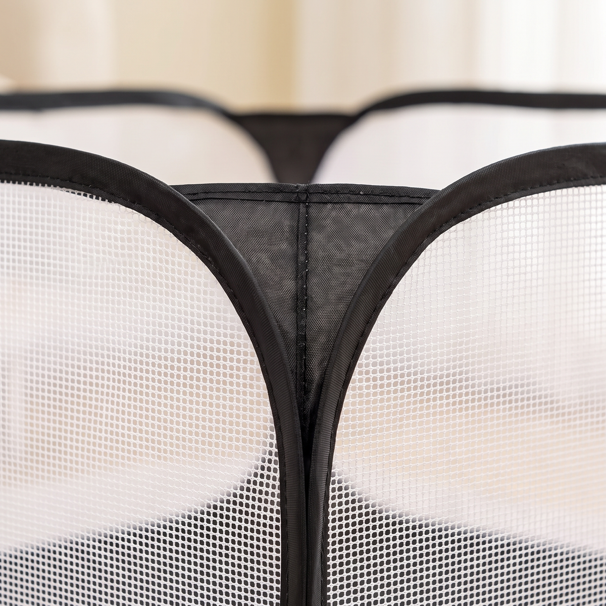 Close-up of the white mesh and black binding where two playpen panels meet