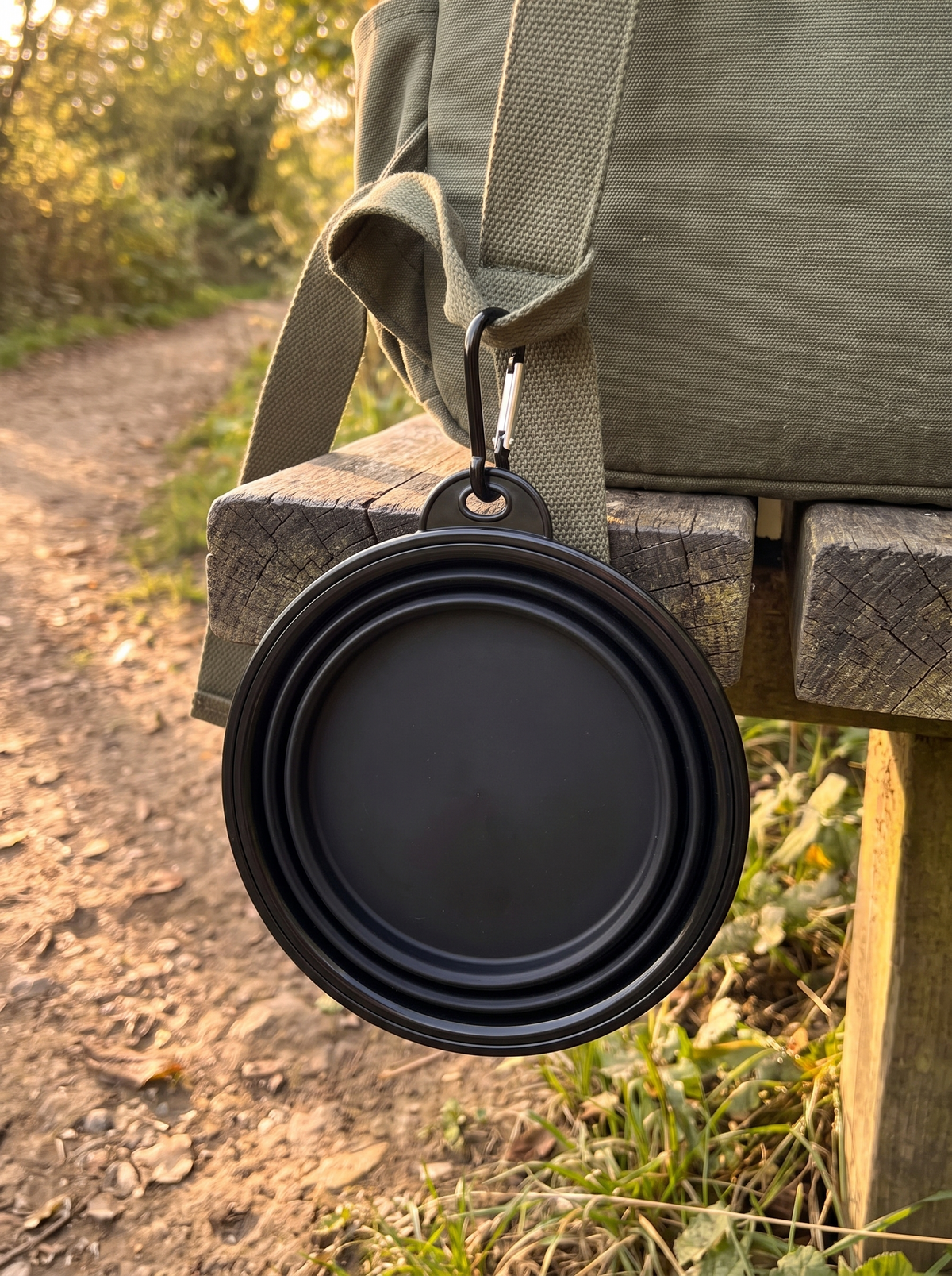 Folded dog travel bowl clipped to a canvas rucksack strap
