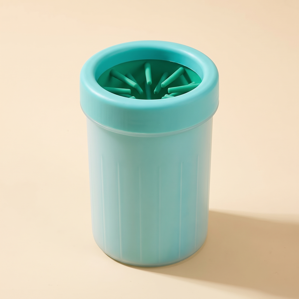 Green dog paw cleaner cup with silicone bristles on a cream background