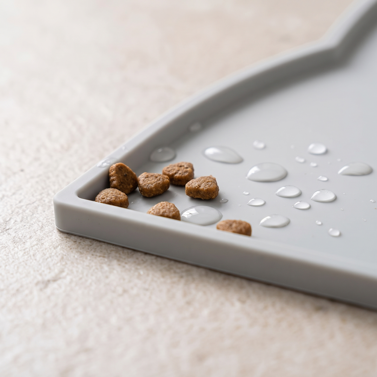 Close-up of the raised edge of a silicone feeding mat holding kibble and water