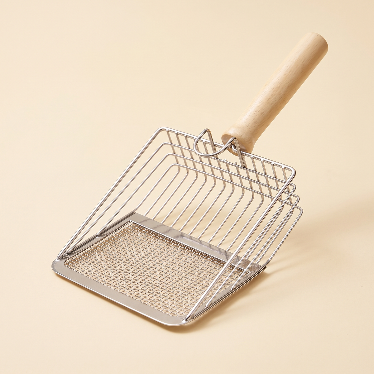 Stainless steel wire cat litter scoop with wooden handle on a cream background
