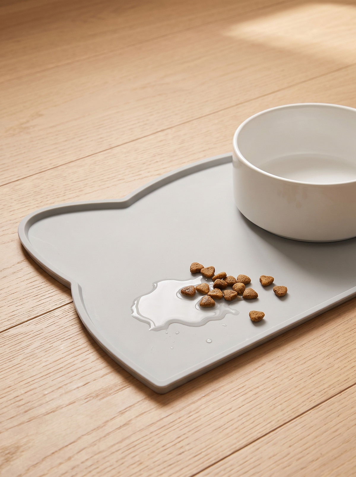 Raised edge of a silicone feeding mat containing spilled water and kibble