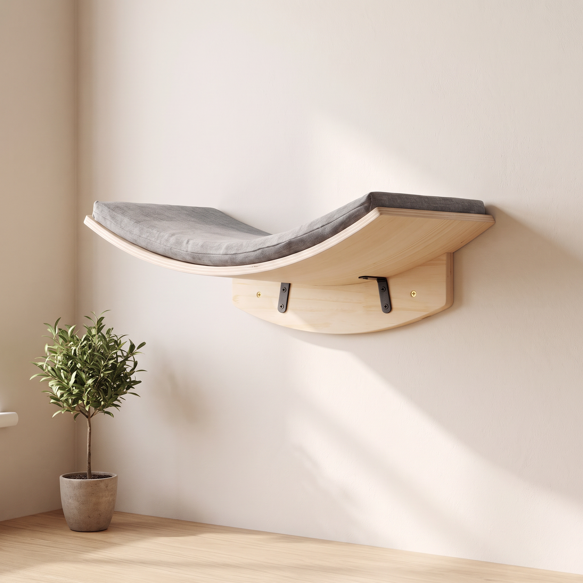 Curved pale pine cat wall cradle with grey felt cushion on black L brackets in a bright cream living room