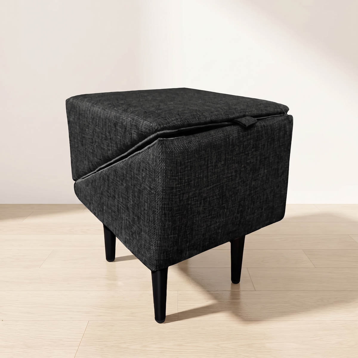 Charcoal grey upholstered dog ramp folded closed as a footstool on black tapered legs
