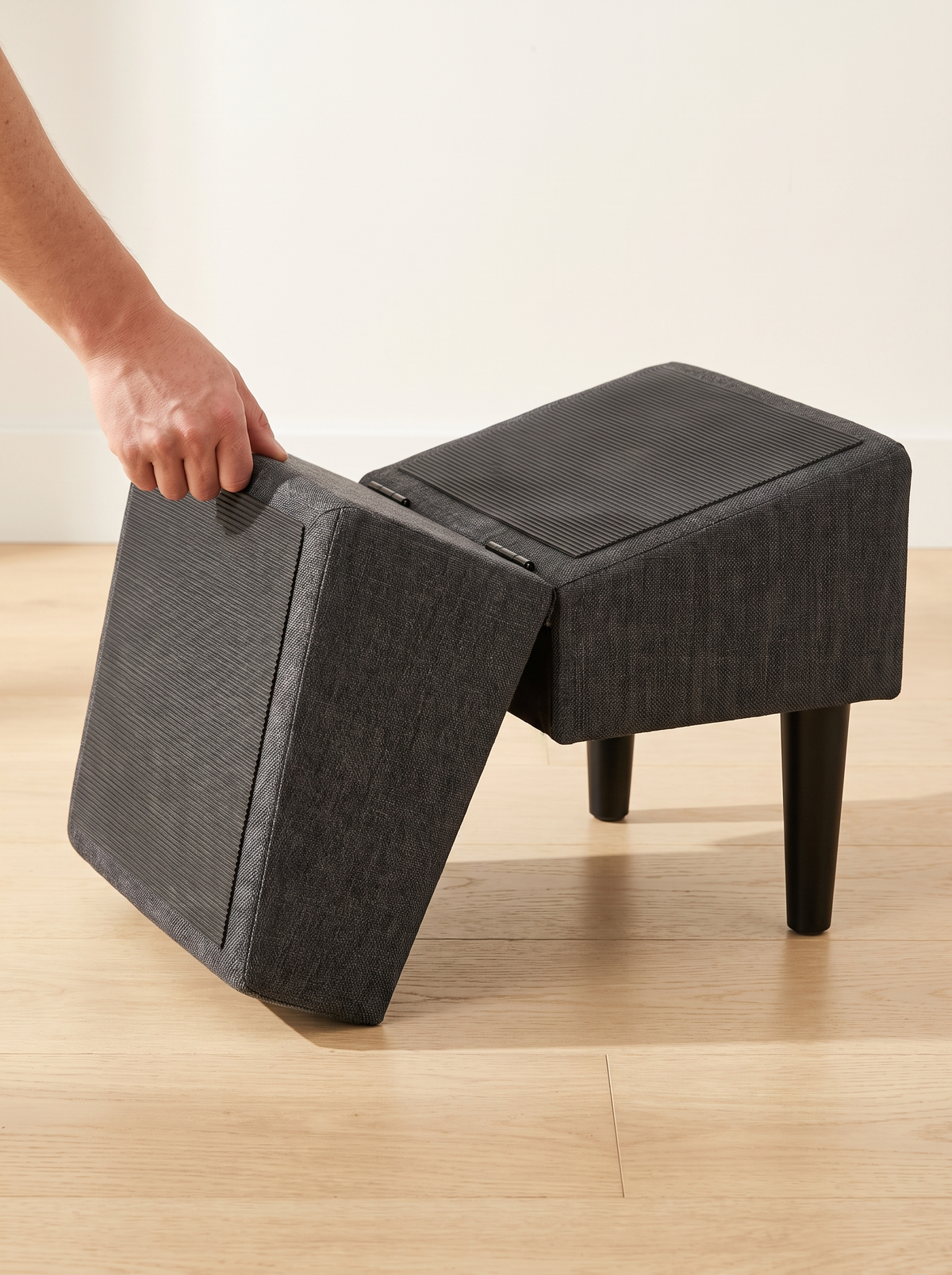Hand opening the charcoal footstool into a dog ramp on its metal hinges